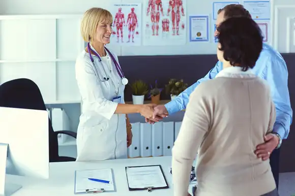 Female doctor handshaking a patient's hand and smiling