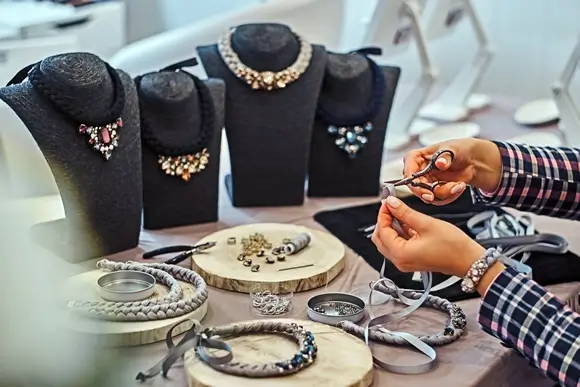 elegantly dressed woman makes handmade necklaces
