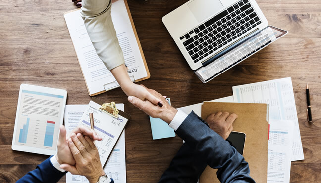 people shaking hands while one person claps in a meeting